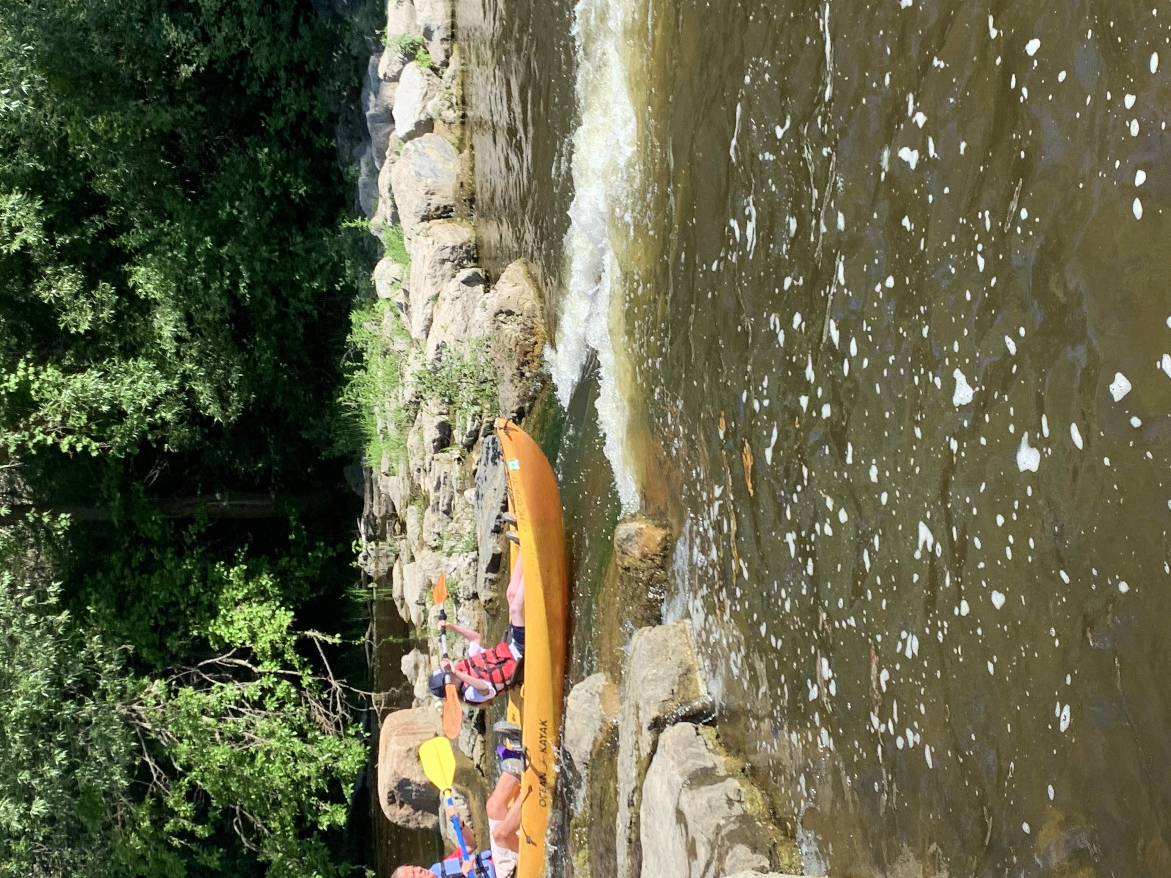  two people on a kayak approaching some small rapids